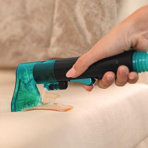 shampouineuse Cecotec Conga 2000 en train d’aspirer une tache liquide sur tissu clair