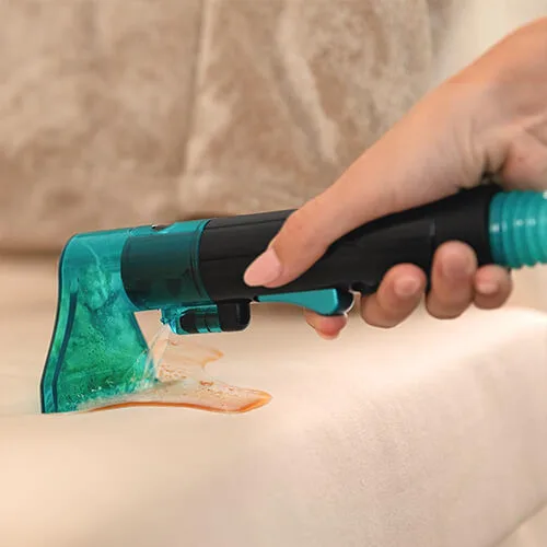 shampouineuse Cecotec Conga 2000 en train d’aspirer une tache liquide sur tissu clair