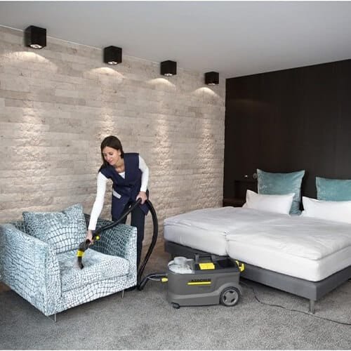 Nettoyage d’un fauteuil en tissu avec la shampouineuse Kärcher Puzzi 10/1 dans une chambre d’hôtel