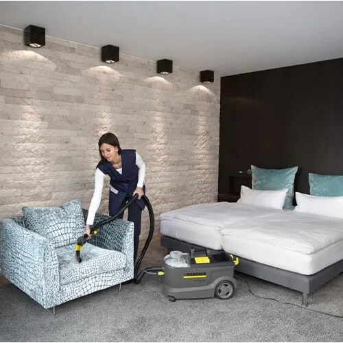 Nettoyage d’un fauteuil en tissu avec la shampouineuse Kärcher Puzzi 10/1 dans une chambre d’hôtel