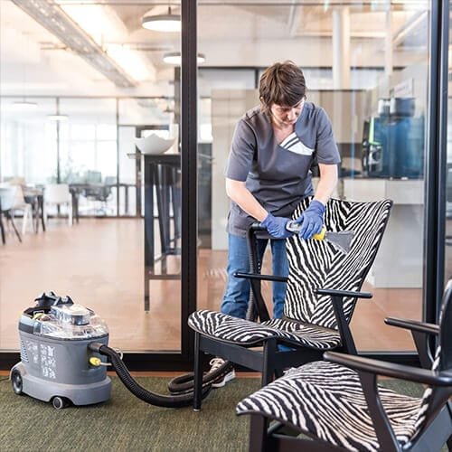 Nettoyage professionnel de chaises en tissu zébré avec la shampouineuse Kärcher Puzzi 8/1 C dans un bureau vitré