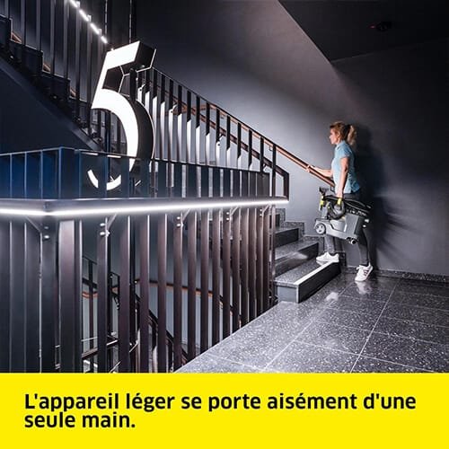 Femme portant facilement la shampouineuse Kärcher Puzzi 8/1 C Karc Waschsauger dans un escalier avec une seule main