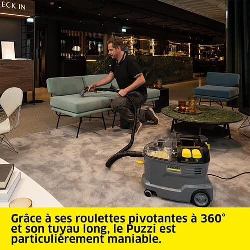 Homme utilisant la shampouineuse Kärcher Puzzi 8/1 C Karc Waschsauger pour nettoyer un fauteuil dans un hall d’hôtel, mettant en avant la maniabilité de l’appareil
