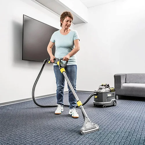 Femme utilisant la shampouineuse Kärcher Puzzi 9/1 Bp Adv pour nettoyer une moquette dans un bureau