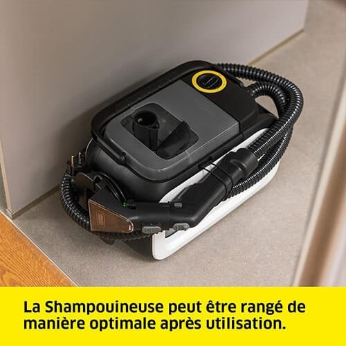 Rangement compact de la shampouineuse Kärcher SE 3 Compact après utilisation, avec tuyaux et accessoires fixés proprement