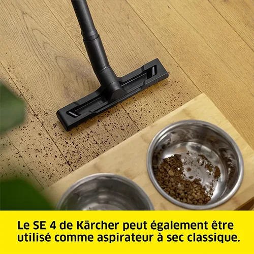 Utilisation de la shampouineuse Kärcher SE 4 en mode aspiration à sec pour nettoyer des miettes sur un sol en bois près d'une gamelle pour chien